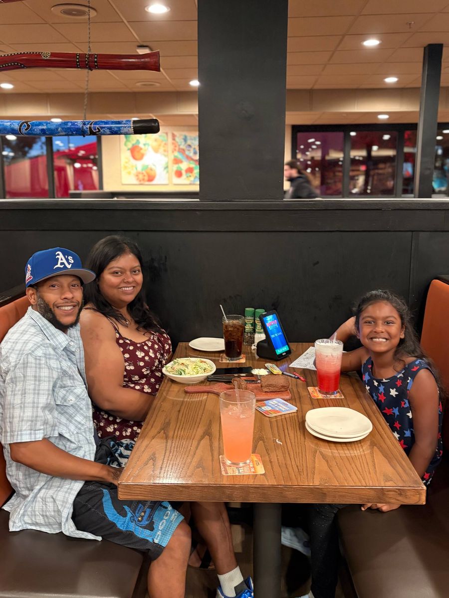 Tommy, Tika and Riya Humphrey smiling together at a restaurant table