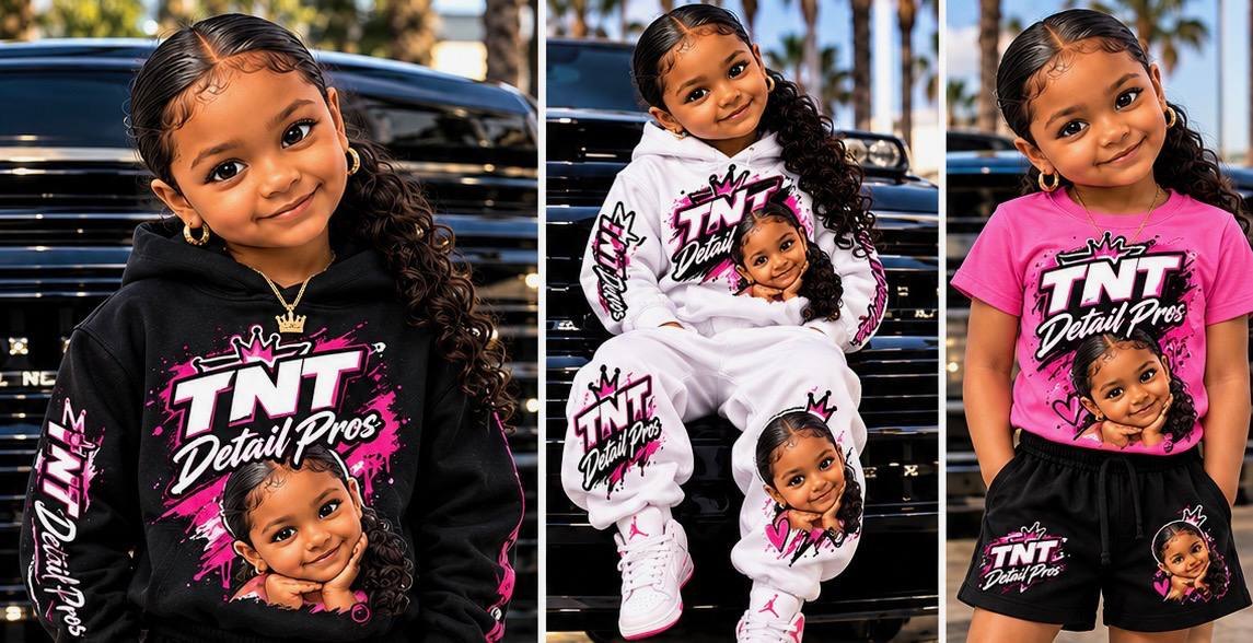 A little girl in black, white and pink TNT Detail Pros outfits in front of a black truck