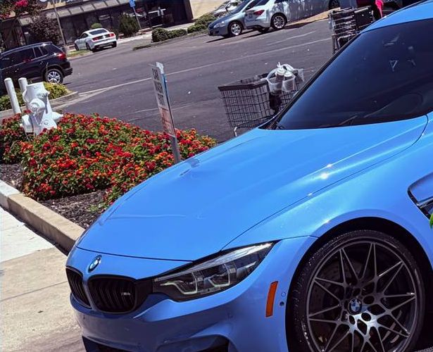 Front of a light blue BMW M4 with dark forged wheels after a detail