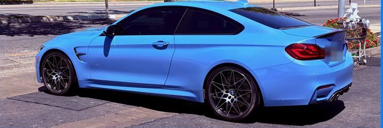 Side view of a light blue BMW M4 coupe with a glossy finish