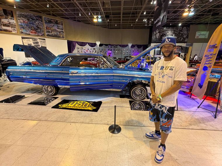 Tommy standing next to a blue lowrider at a car show